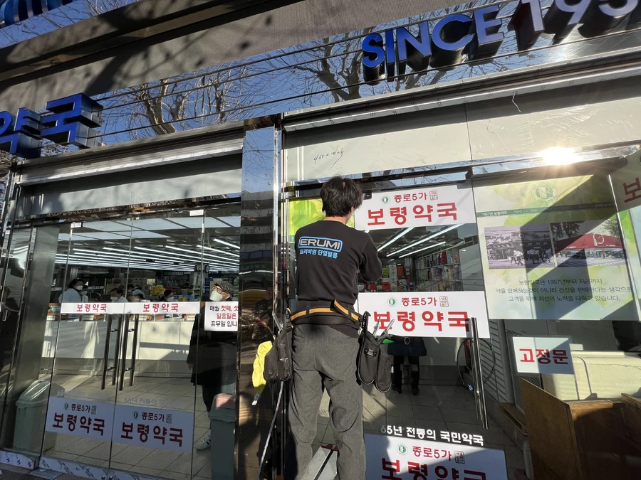 약국 자동문 열차단필름 시공 중 – 전문 기사 작업